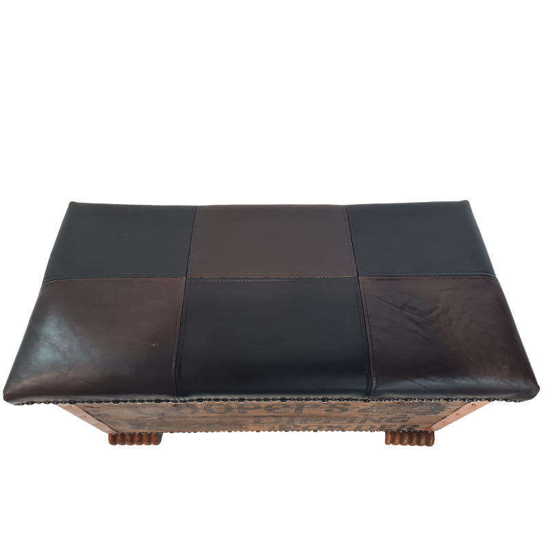 A rectangular leather bench with a patchwork design in black and dark brown, featuring a carved wooden base with decorative molding and small turned legs.