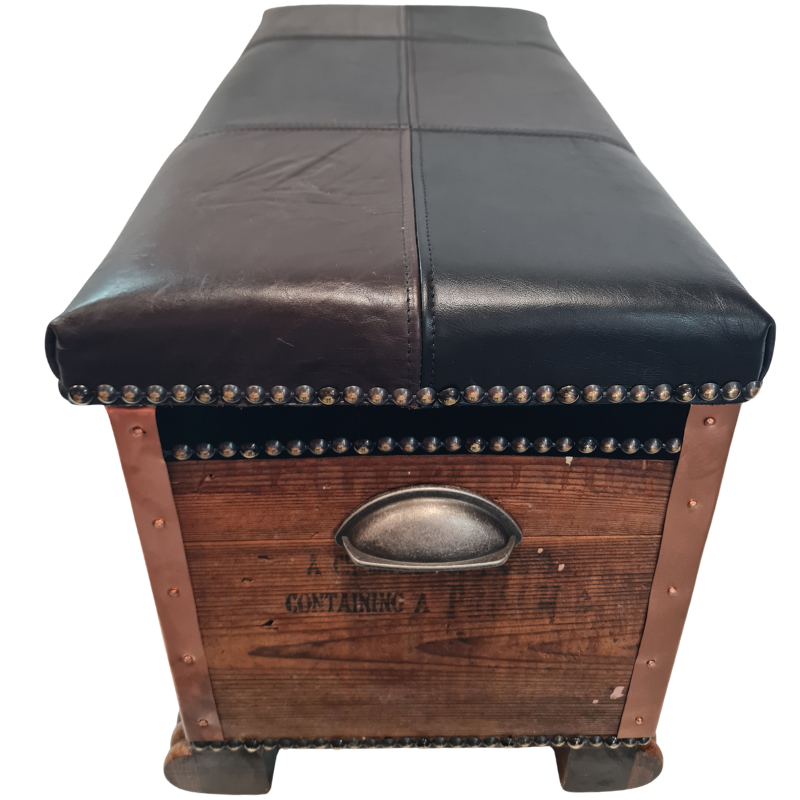A vintage-style trunk bench with a dark brown leather cushioned top and a rustic wooden body, featuring brass nailhead trim and a metal oval handle on the front.