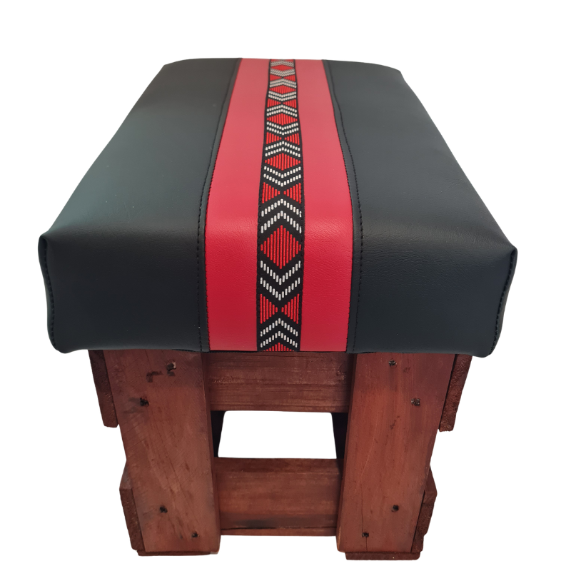 Black and red footstool with a red and a maori patterned braid  on a white background