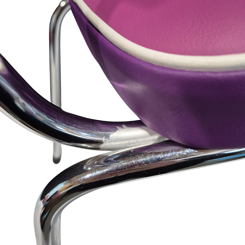 Close-up of a mid-century modern chair featuring a purple upholstered seat with a white edge, supported by a curved polished chrome tubular steel frame. Showing anti rust paint over rusty area. 